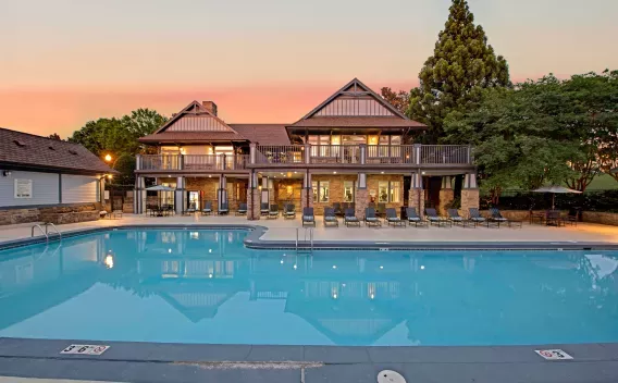 A serene swimming pool with a Tudor-style clubhouse and ambient evening lighting.