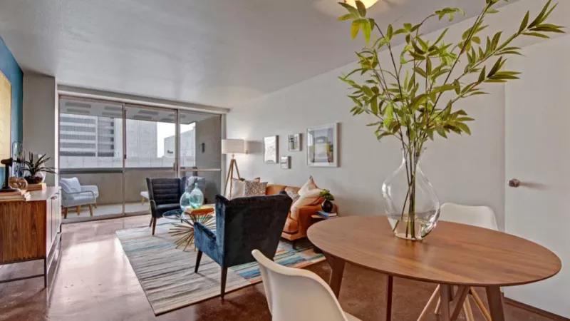 A stylish living room with a vibrant blue accent wall, a tan couch, and eclectic decor.
