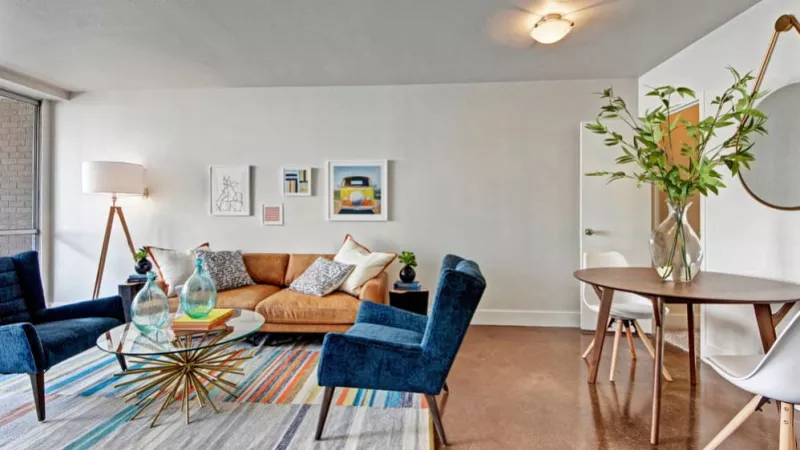  A bright living room featuring modern furniture and a colorful rug.