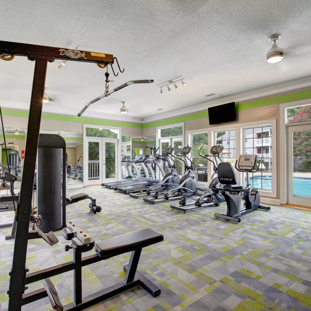 Another angle of the fitness center, highlighting advanced workout equipment and a view of the pool through large windows.