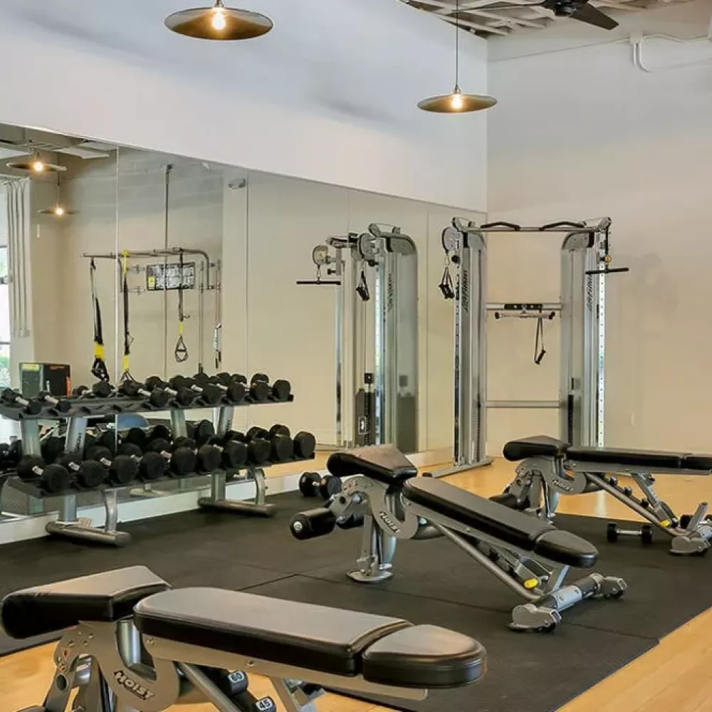Gym with weight training equipment, benches, and large mirrors for functional workouts.