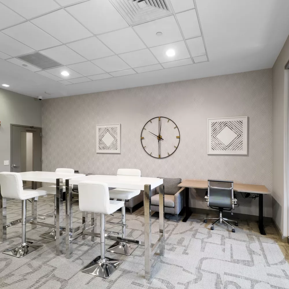 The resident business center includes communal high-top tables for coworking and a glass-enclosed meeting space.