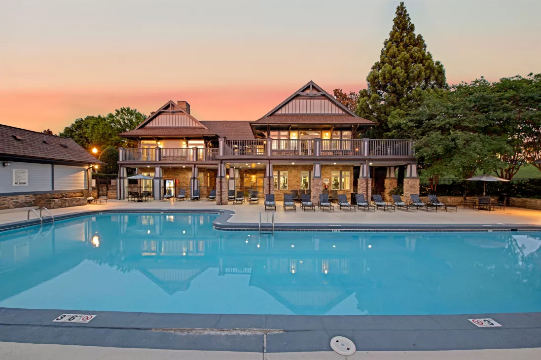 A serene swimming pool with a Tudor-style clubhouse and ambient evening lighting.