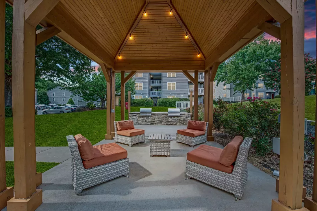 A cozy outdoor seating area under a wooden gazebo with soft lighting at 200 Braehill Apartments.