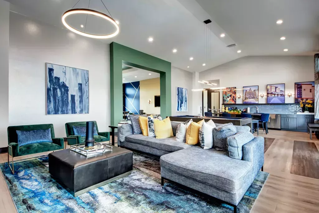 Modern resident clubhouse interior at 32Hundred Windsor Apartments in Denton, TX, featuring stylish lounge seating, contemporary décor, vibrant artwork, and open-concept co-working and kitchen spaces.