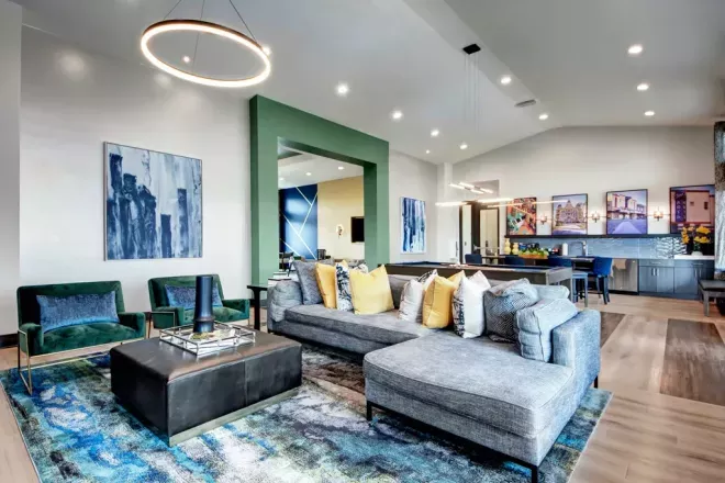 Modern resident clubhouse interior at 32Hundred Windsor Apartments in Denton, TX, featuring stylish lounge seating, contemporary décor, vibrant artwork, and open-concept co-working and kitchen spaces.